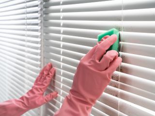 Person using a microfiber cloth to clean blinds